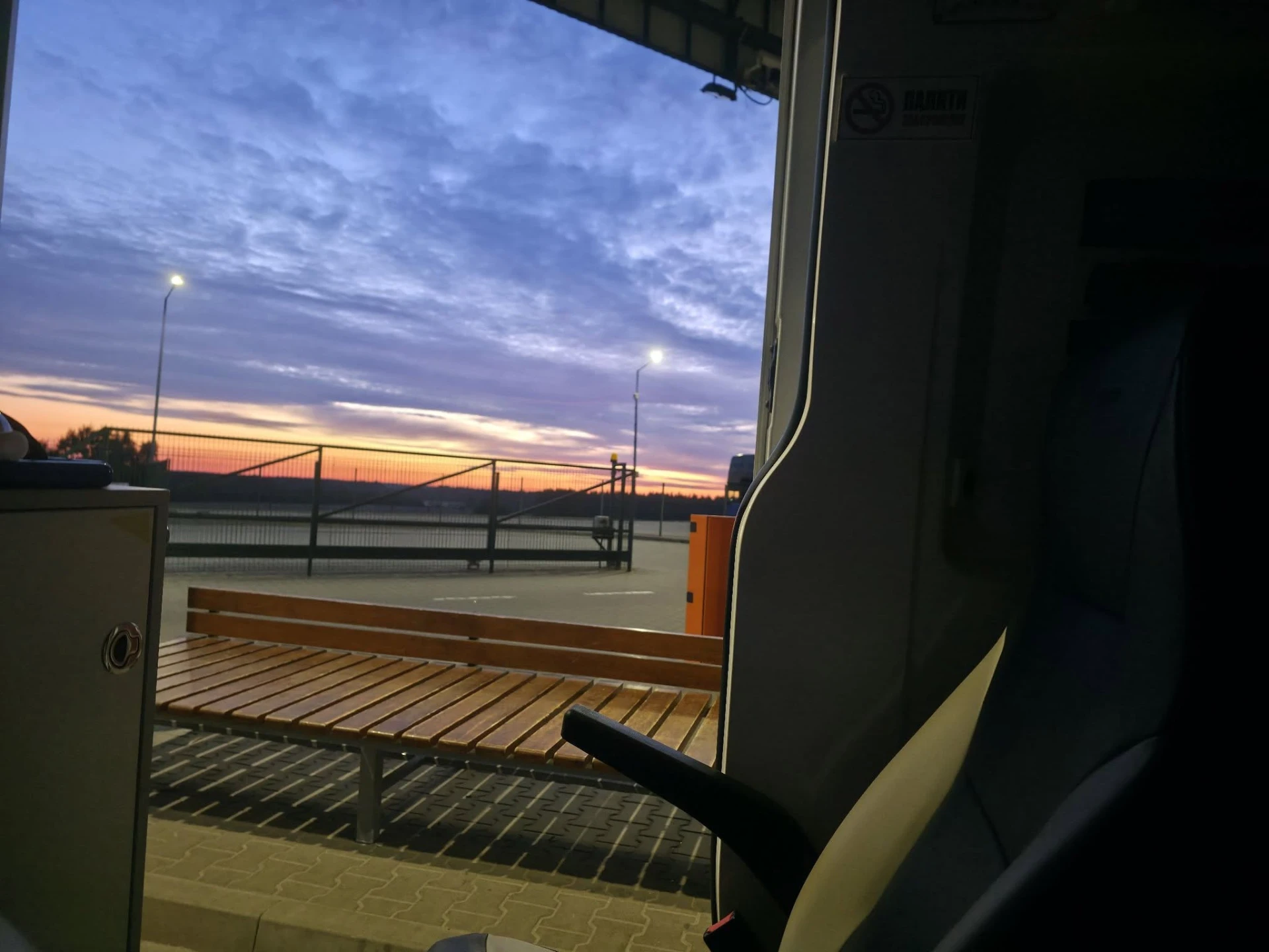Sunset seen through a bus window over a quiet Ukrainian road stop in 2026