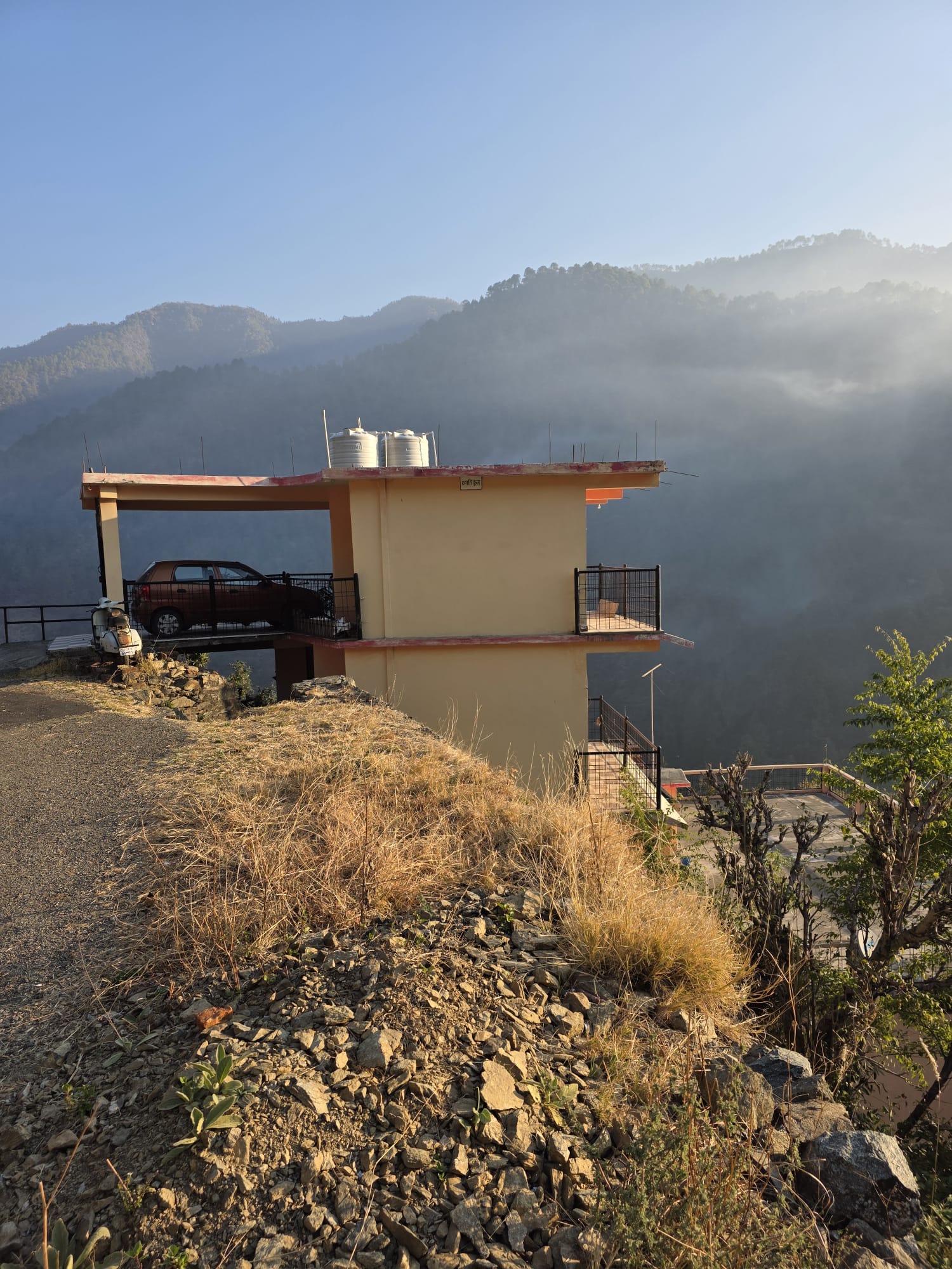 Building on a hillside in the Himalayan foothills with morning mist over the valley