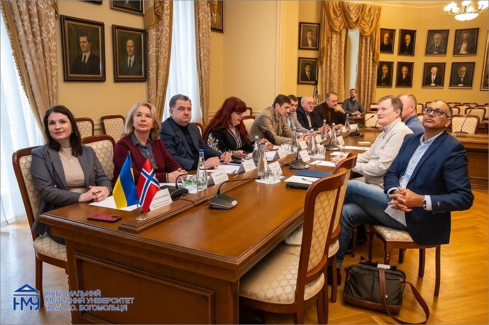 Delegation seated around the meeting table with Ukrainian and Norwegian flags at Bogomolets National Medical University
